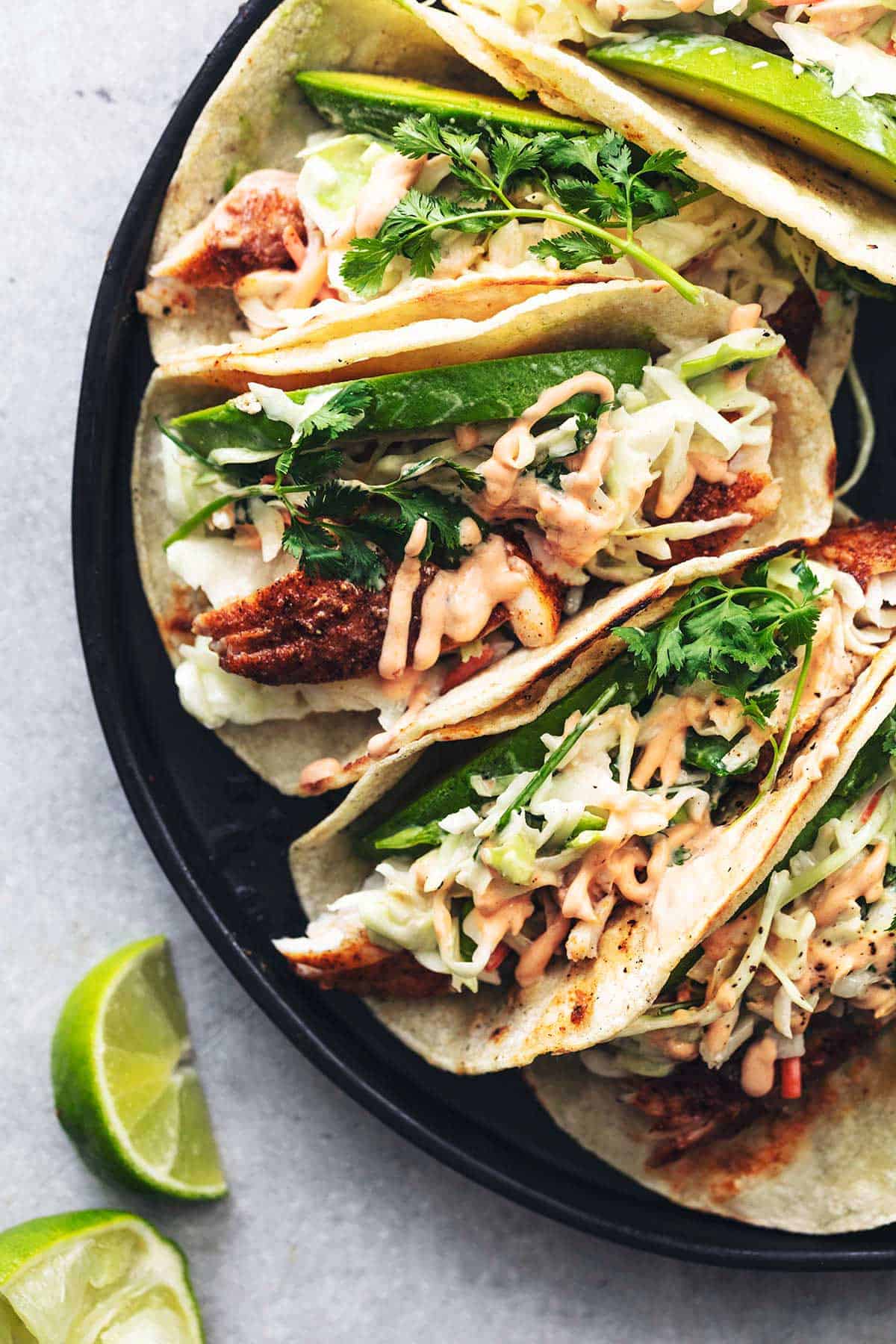 overhead view of plate of tacos with limes on table