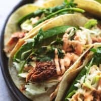 up close fish tacos with slaw and avocado slices on plate