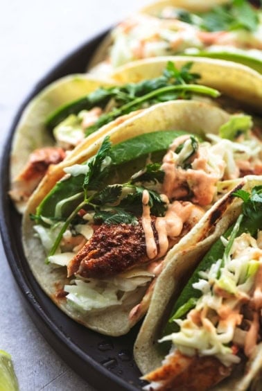 up close fish tacos with slaw and avocado slices on plate