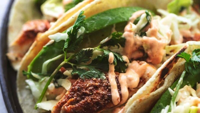 up close fish tacos with slaw and avocado slices on plate