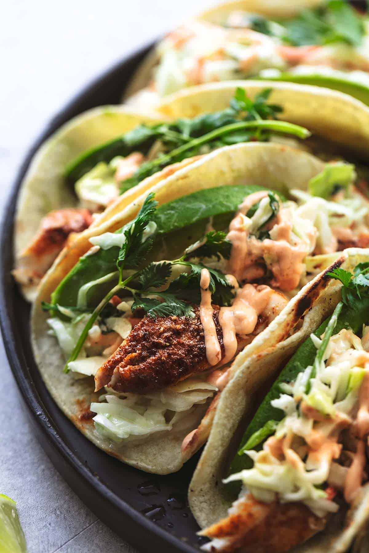 up close fish tacos with slaw and avocado slices on plate