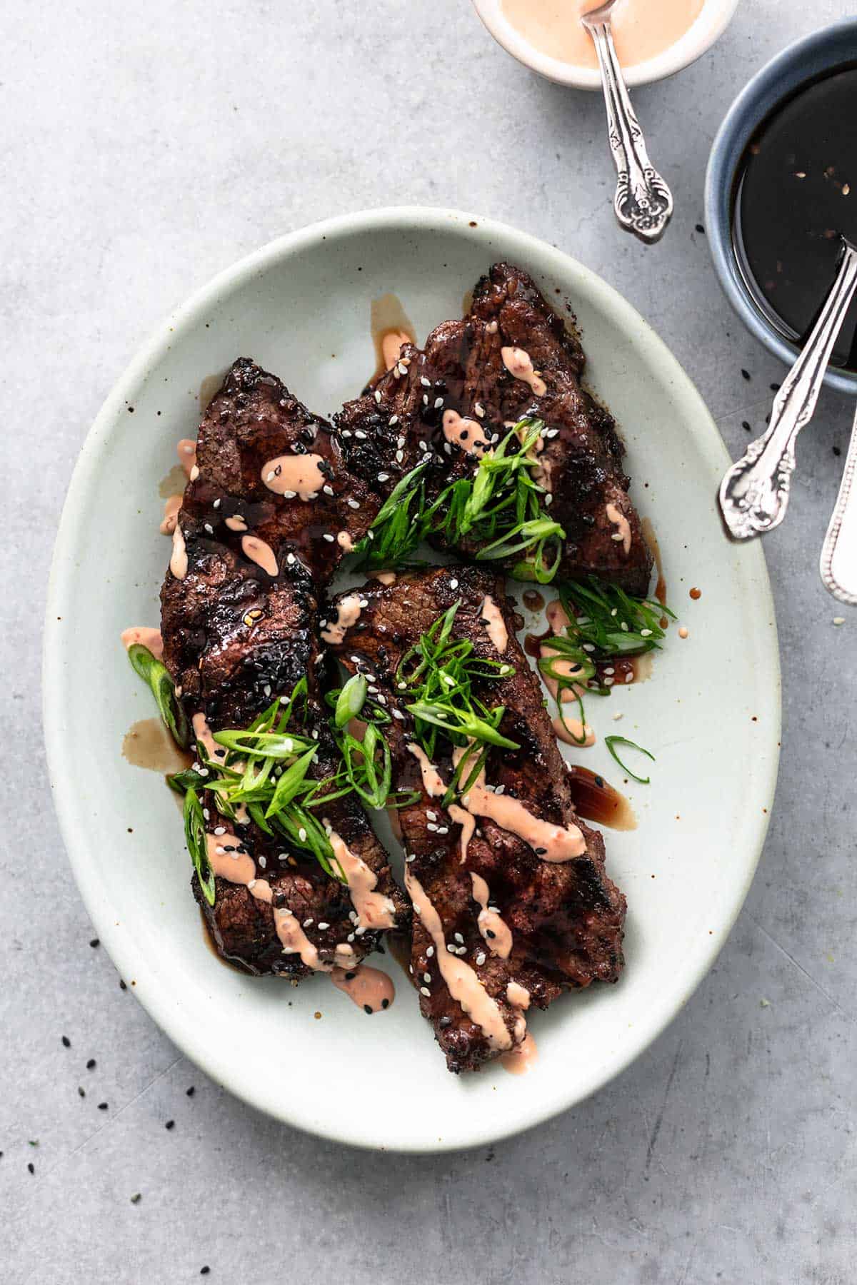 grilled steaks on platter with two bowls of sauce on side