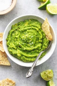 guacamole with spoon and tortilla chips dipped