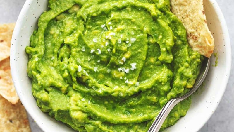 guacamole with spoon and tortilla chips dipped