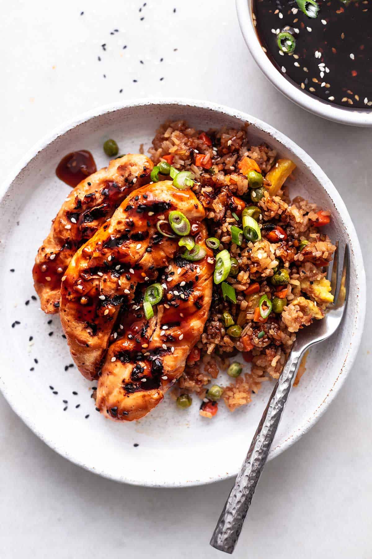 teriyaki chicken and rice with bowl of sauce on table