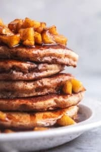 stack of apple cinnamon pancakes with apple topping and syrup