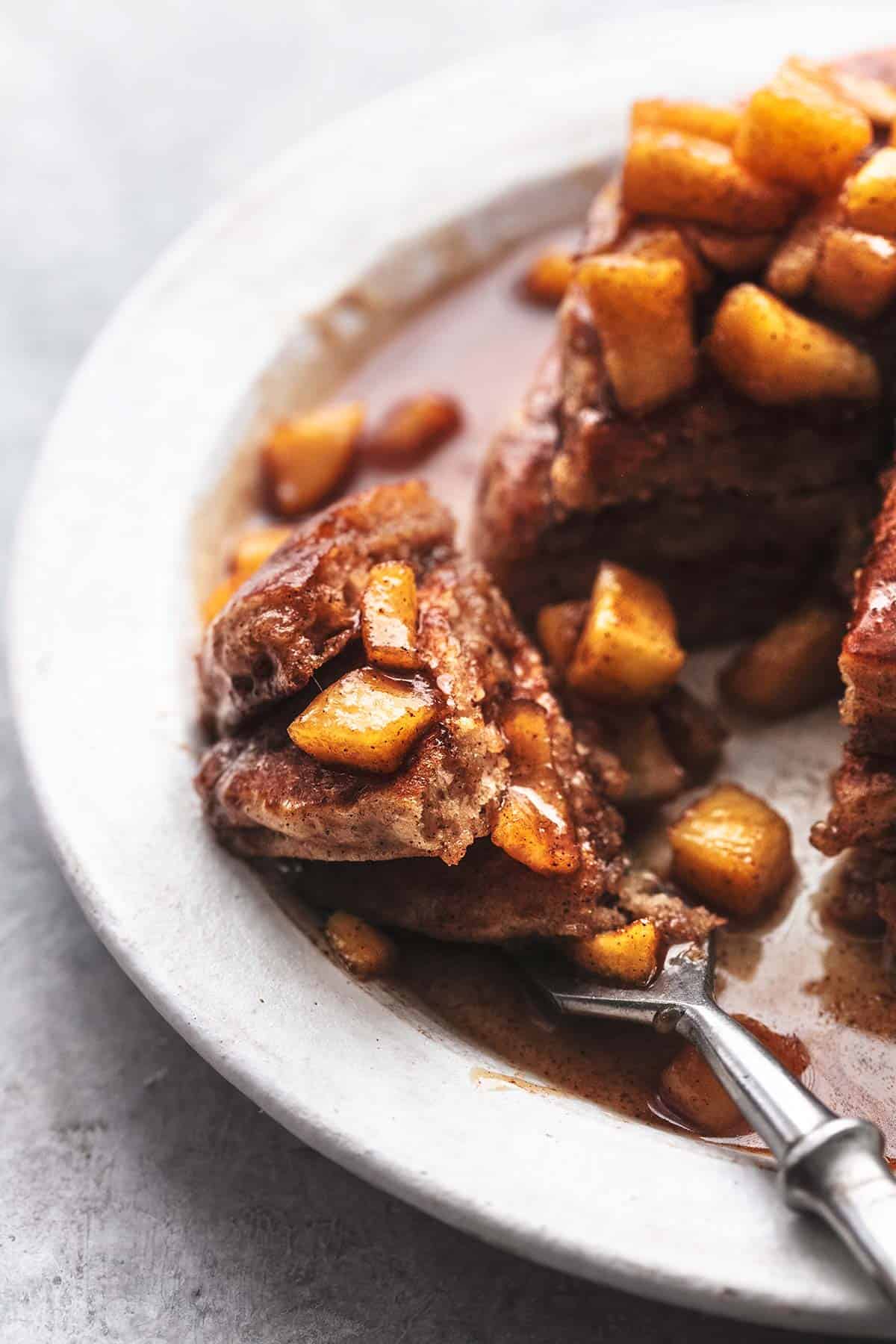 up close view of fork with pieces of pancakes and syrup with fruit chunks