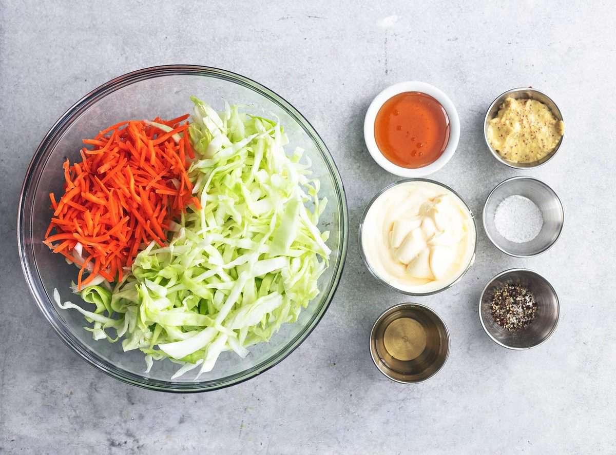 shredded cabbage and carrots in a bowl beside pinch bowls with ingredients