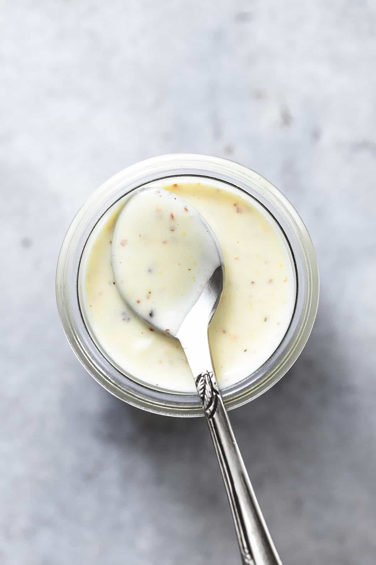 overhead view of cole slaw dressing in a jar with a spoon holding some dressing