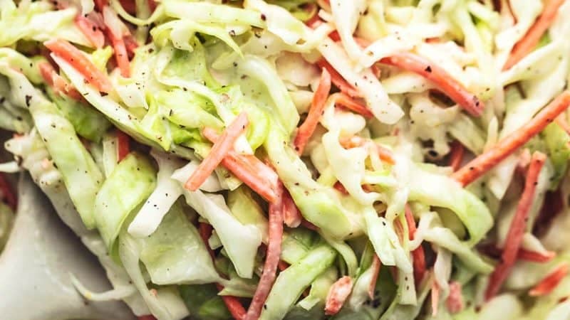 up close shredded cabbage and carrots tossed in creamy dressing