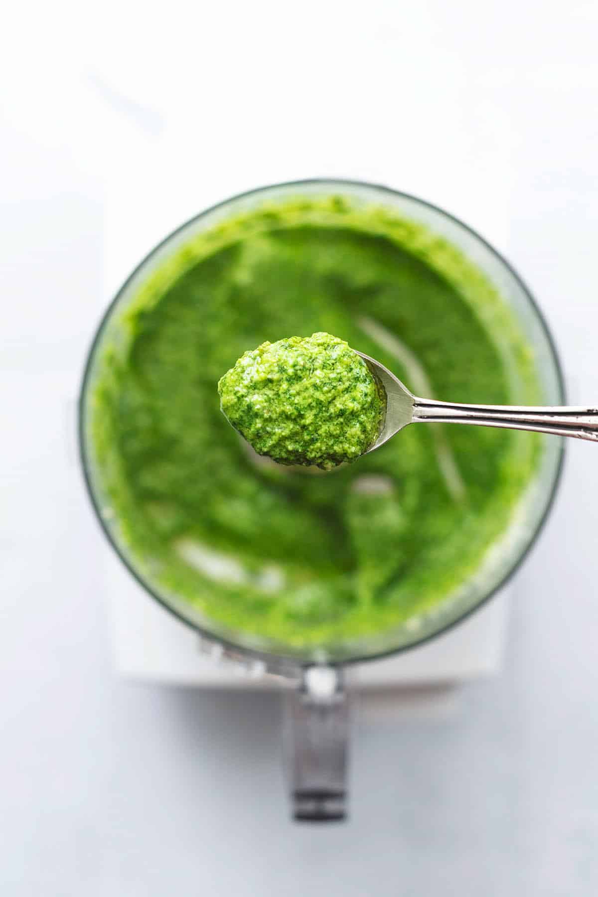 spoon of herb sauce above food processor