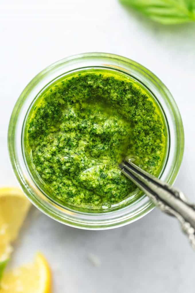 pesto in glass jar with spoon and lemon wedges