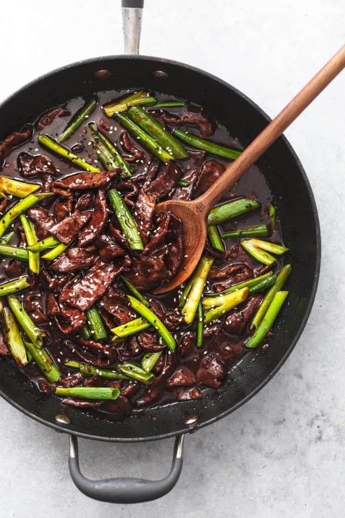 sauteed beef and onions in sauce with serving spoon in skillet