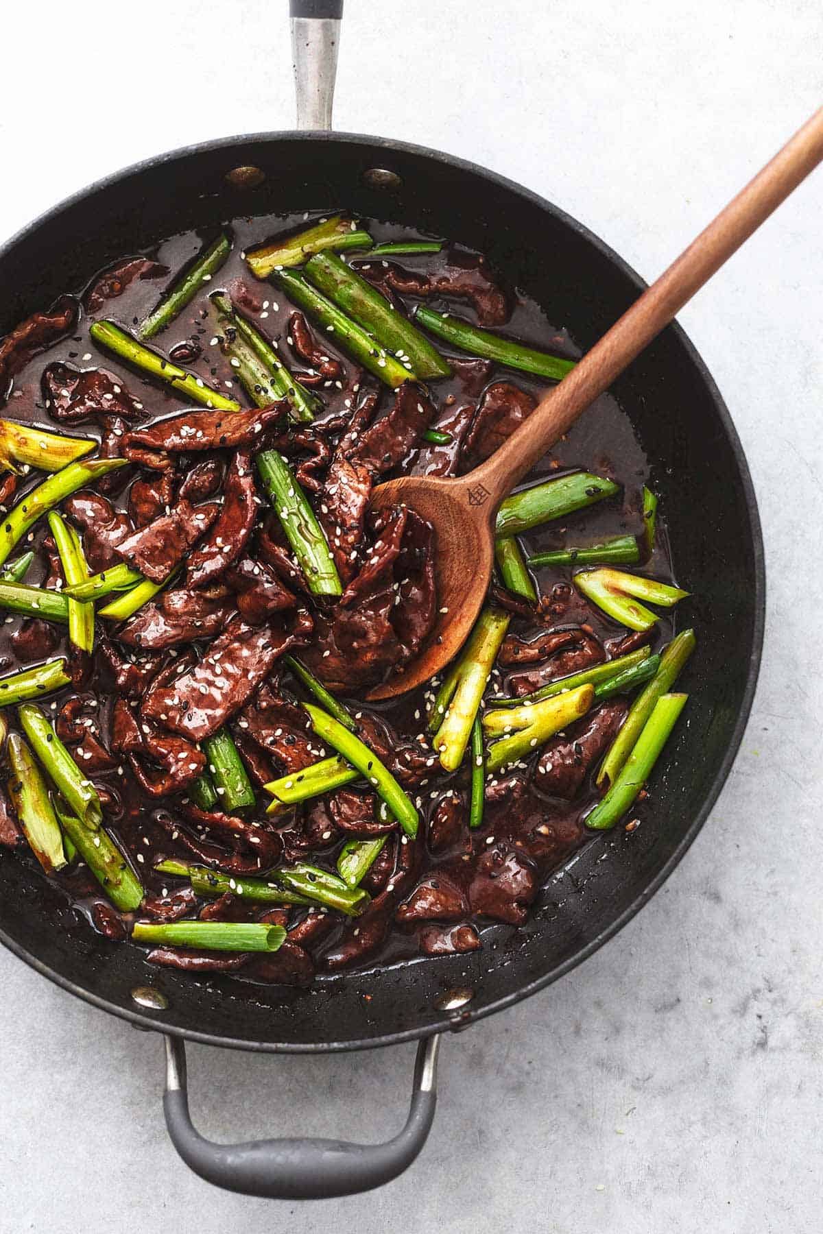 sauteed beef and onions in sauce with serving spoon in skillet