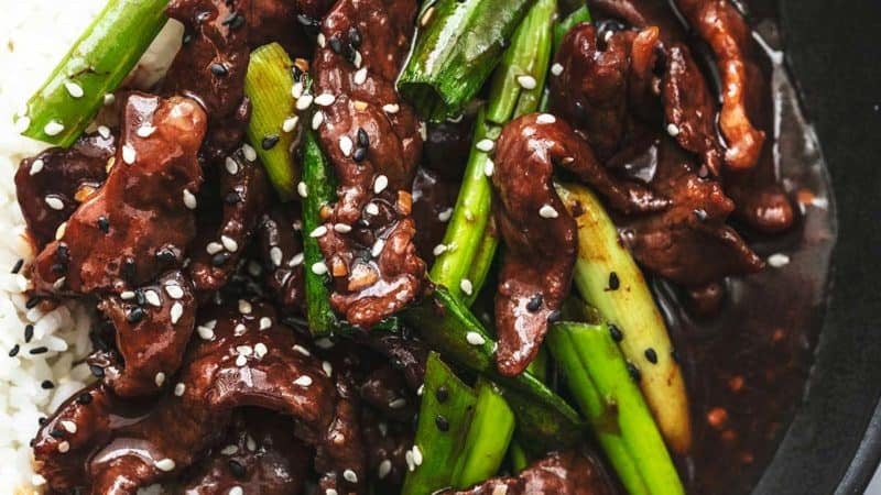 up close view of beef strips with green onions and rice topped with sesame seeds