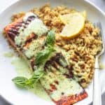 pesto salmon with orzo and lemon wedges on plate
