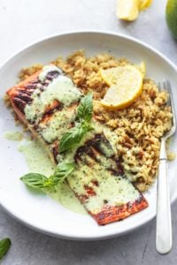 pesto salmon with orzo and lemon wedges on plate