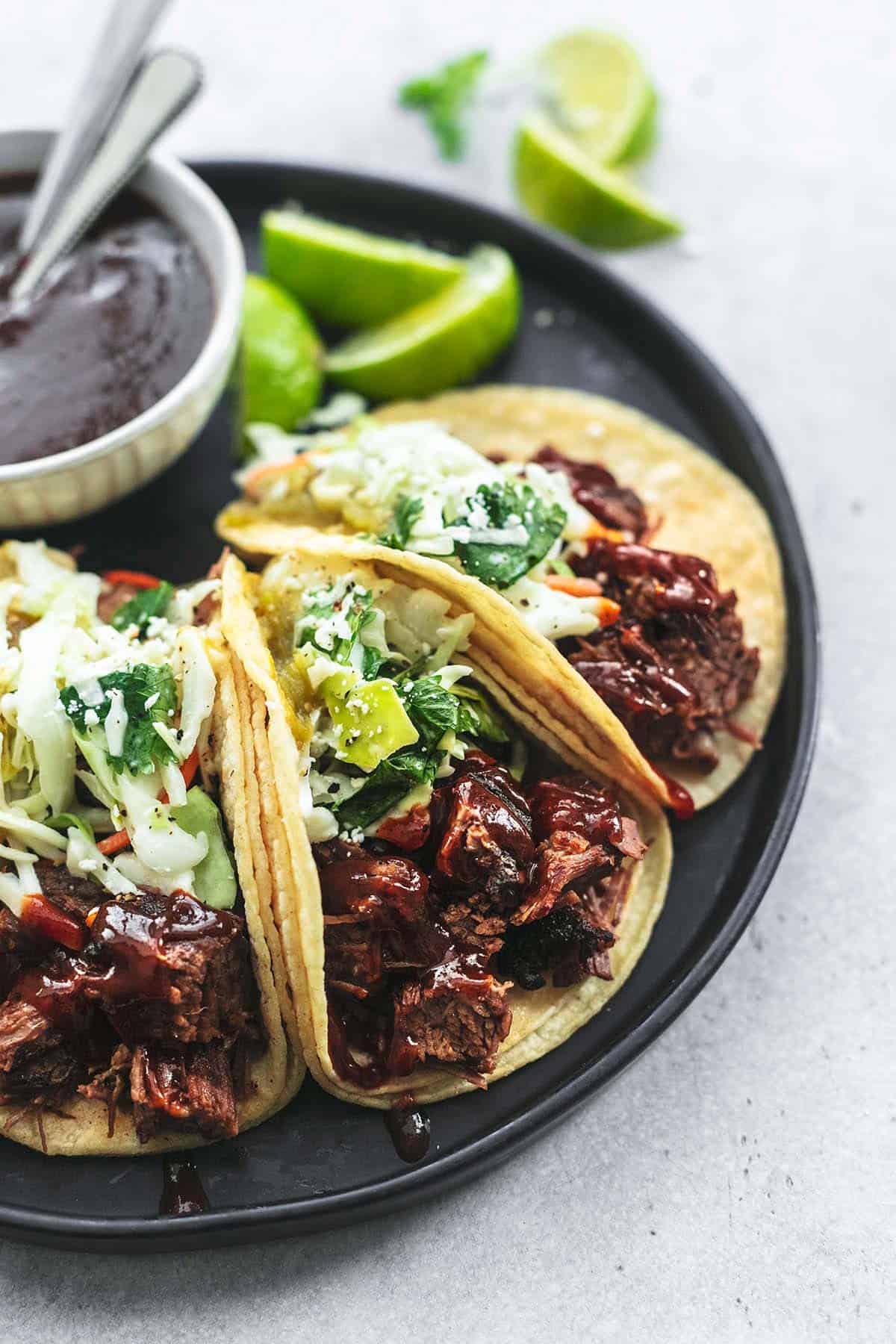 beef brisket tacos with bbq sauce and lime wedges on platter