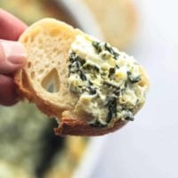 hand holding bread with spinach dip on it