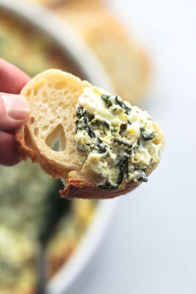 hand holding bread with spinach dip on it