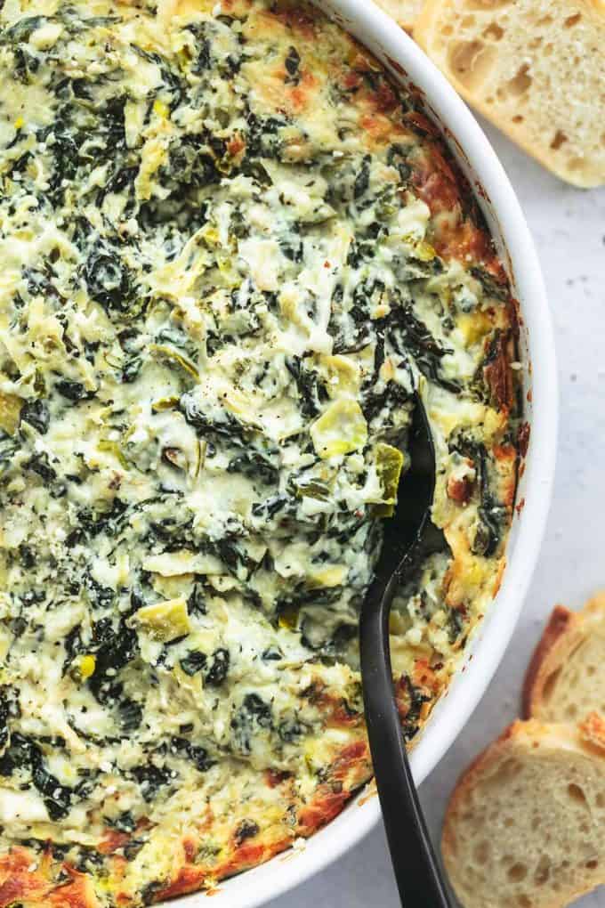 up close spoon scooping spinach artichoke dip