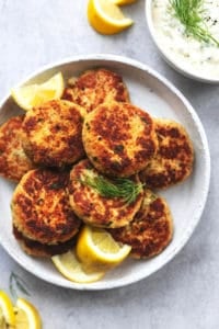 platter of crab cakes with lemon wedges and fresh dill