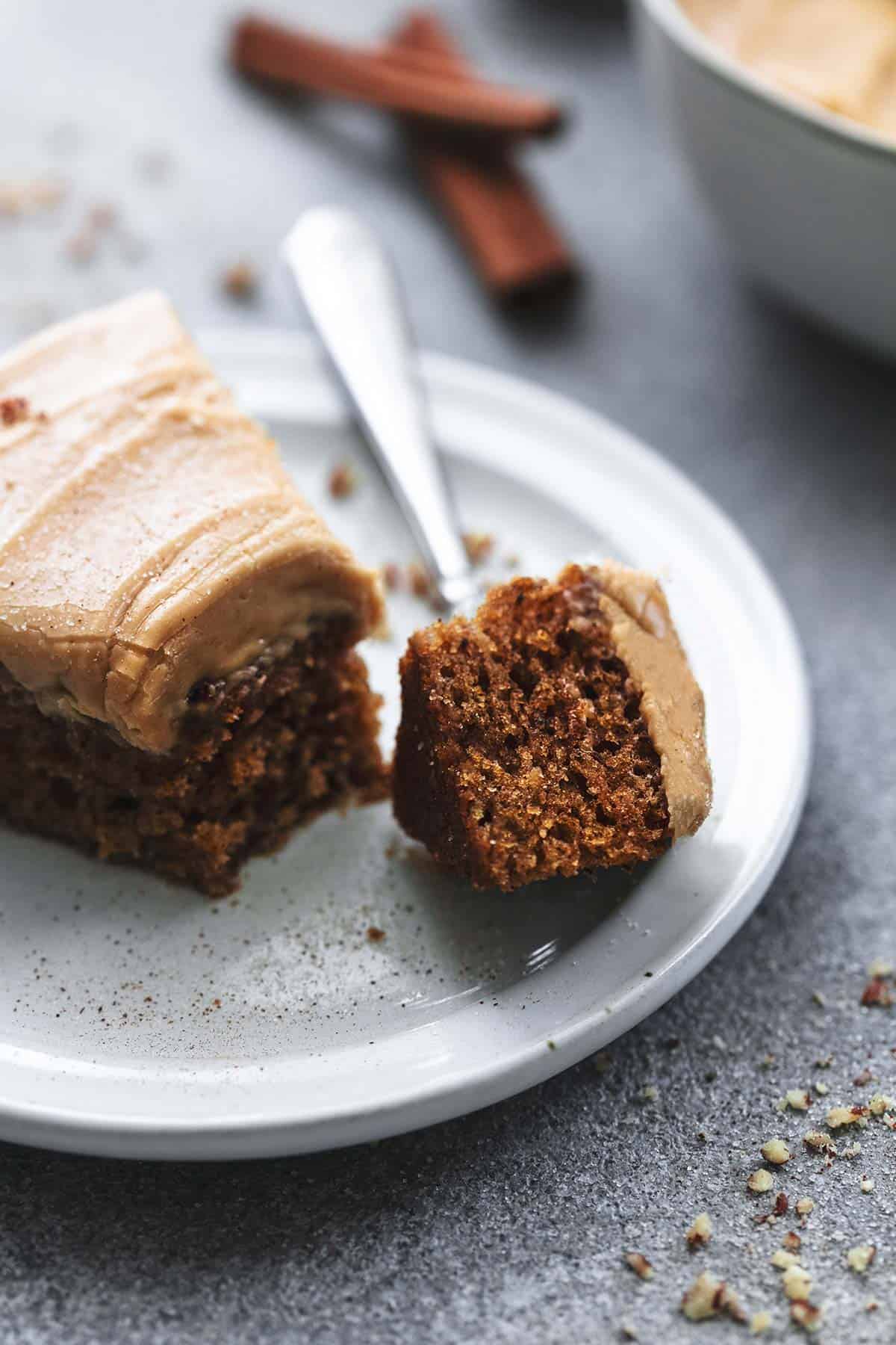 fork cutting into a piece of cake with frosting on plate