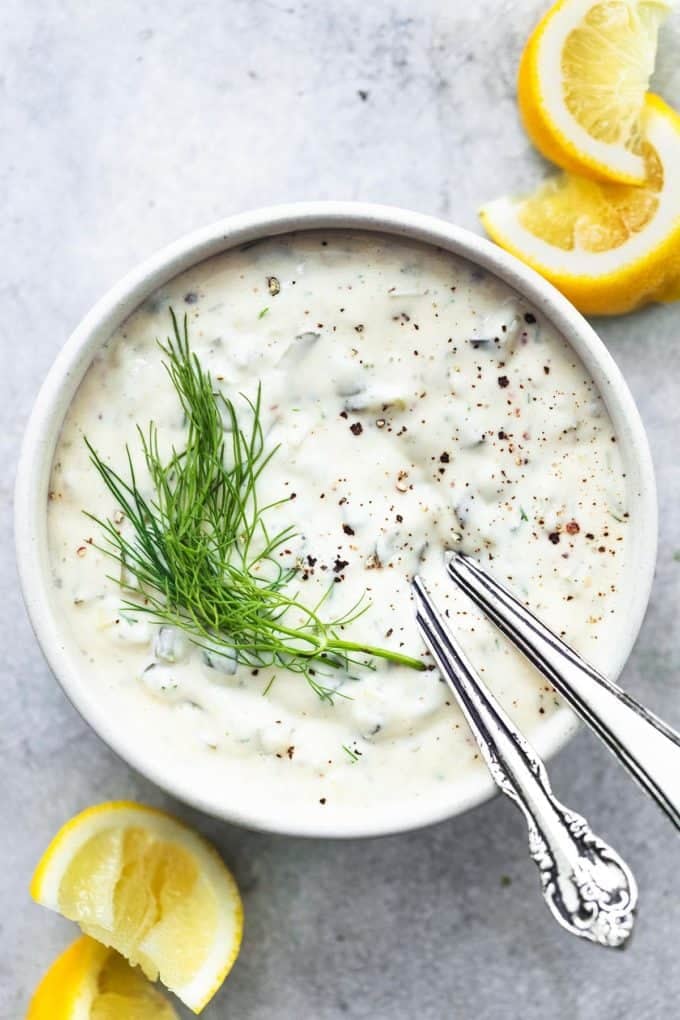 bowl of tartar sauce and lemon wedges on table