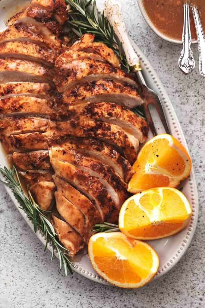 overhead view of sliced turkey breast on platter with oranges and rosemary