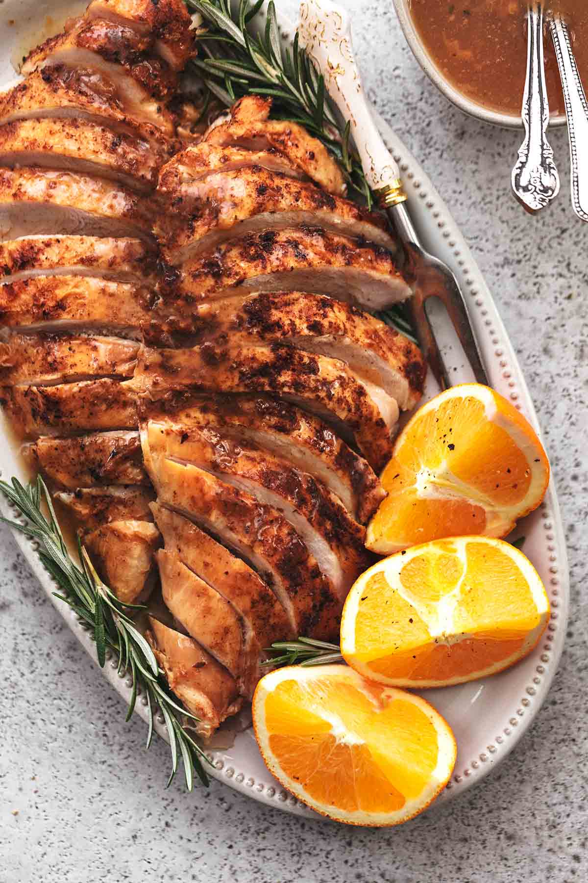 overhead view of sliced turkey breast on platter with oranges and rosemary