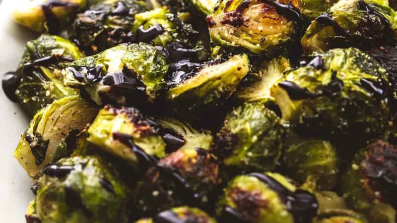 cooked brussels sprouts on platter with balsamic reduction drizzle
