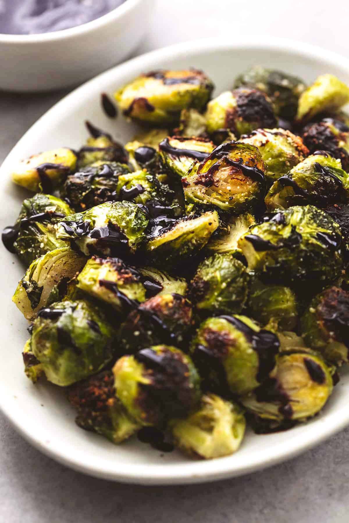 cooked brussels sprouts on platter with balsamic reduction drizzle