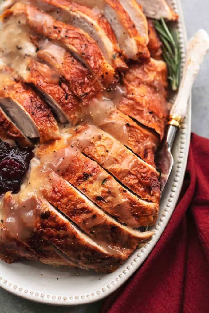 up close sliced thanksgiving turkey on serving platter with fresh rosemary
