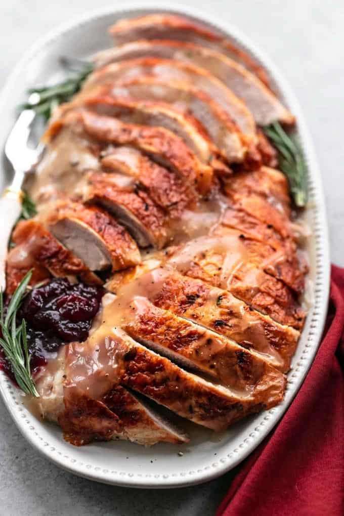 sliced cooked turkey on a platter with cranberry sauce
