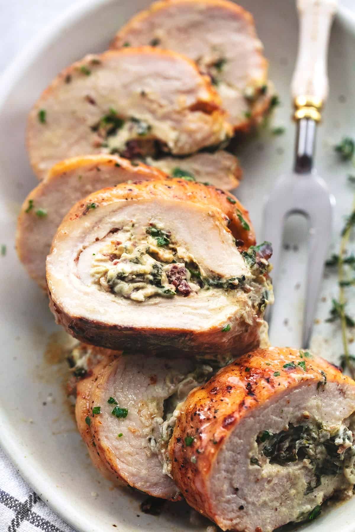 up close single slice of stuffed turkey breast atop more pieces on a plate