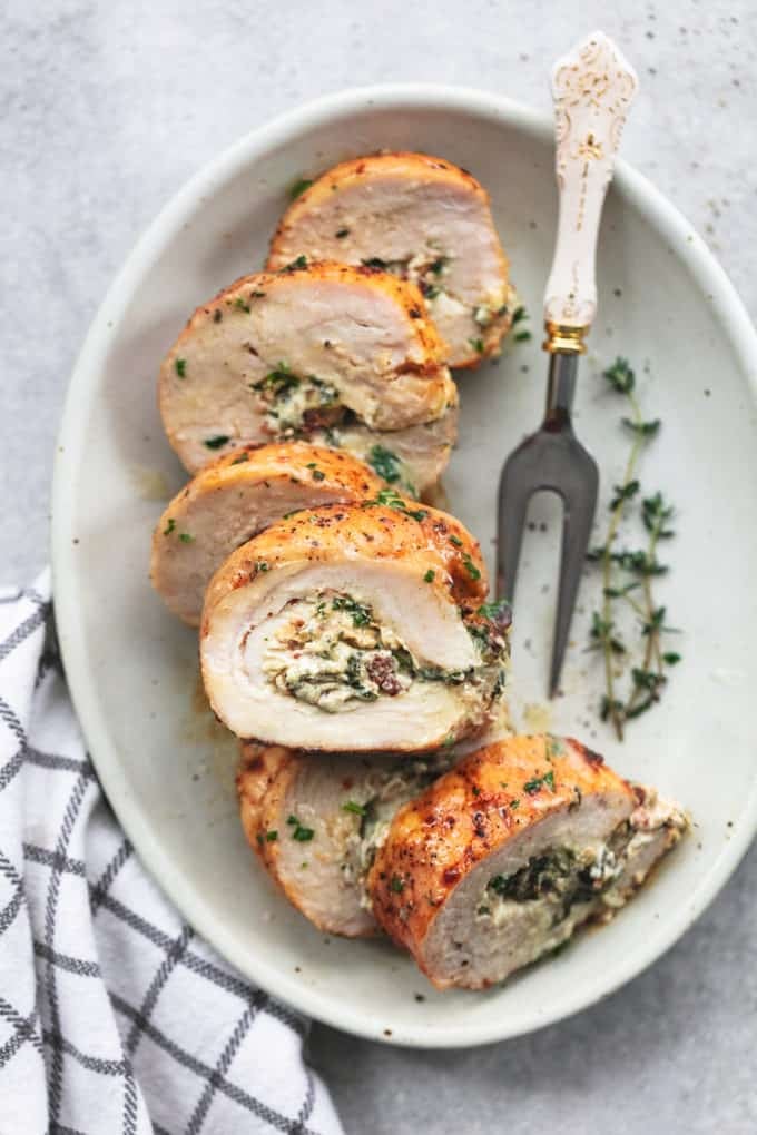 prepared turkey tenderloin with spinach filling on a plate with fresh herbs