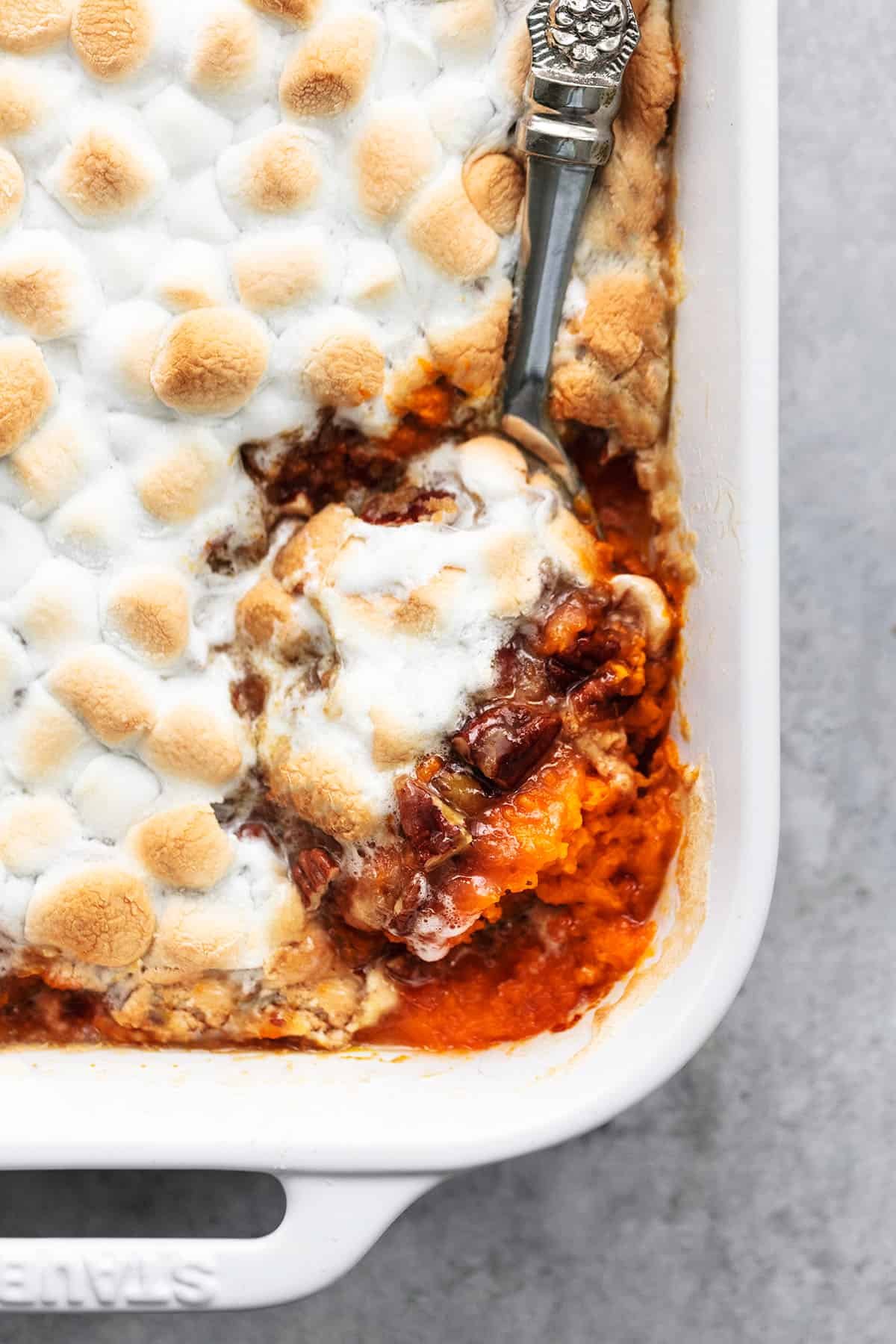 serving spoon in casserole dish of mashed sweet potatoes with pecan topping