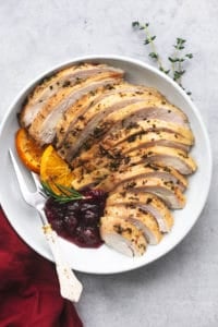 roasted and sliced turkey on platter with cranberry sauce