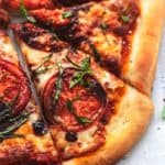 four slices of pizza with tomatoes, cheese, balsamic, and basil