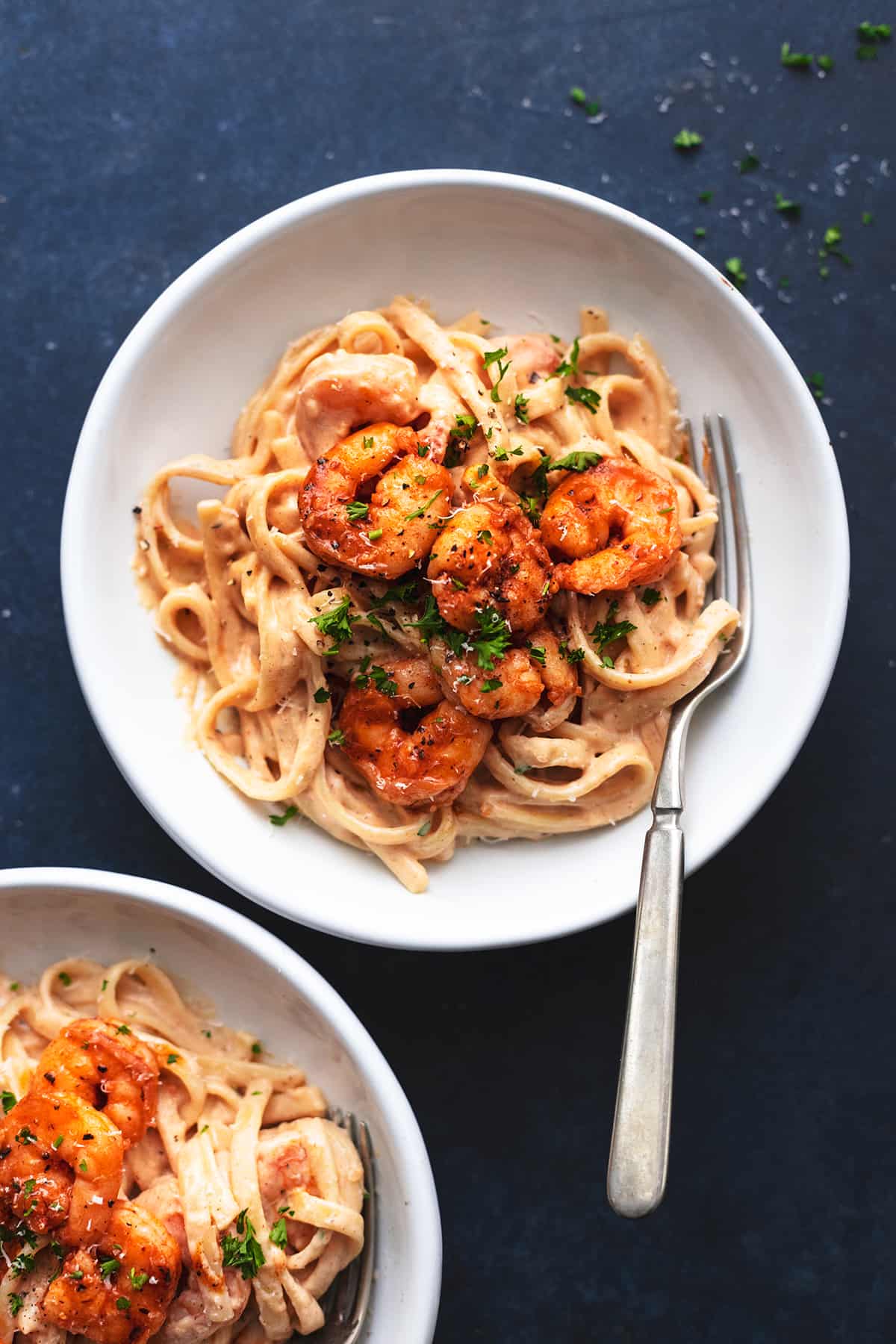 one plate and a partial plate of shrimp alfredo