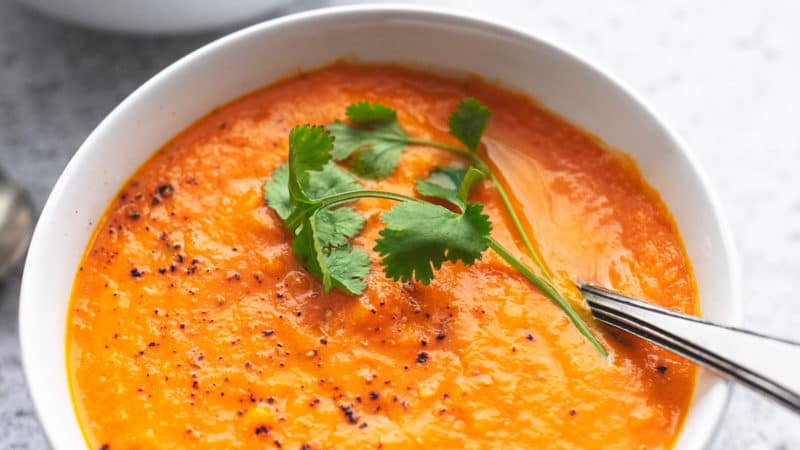 bowl of carrot soup with fresh cilantro garnish and spoon
