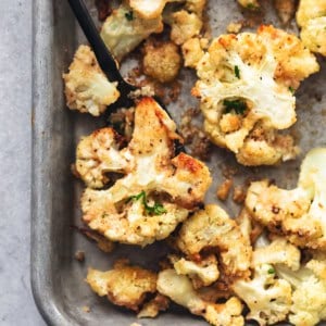 roasted cauliflower on a baking sheet with a serving fork