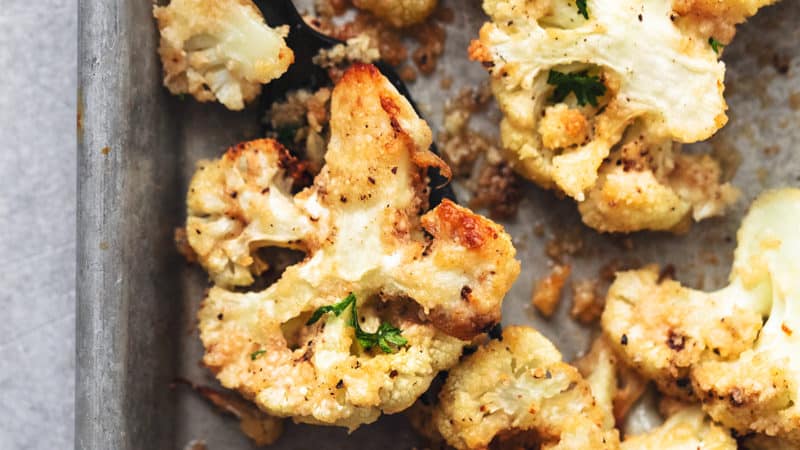 roasted cauliflower on a baking sheet with a serving fork