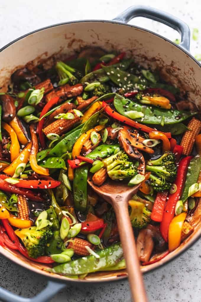 wooden serving spoon stirring vegetables in skillet