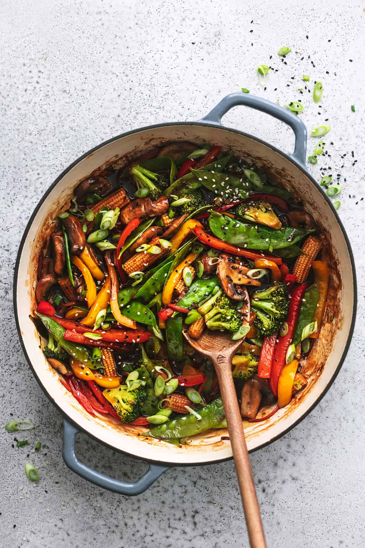 overhead view of wooden spoon stirring vegetables in pan