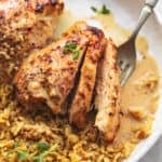 up close view of sliced, cooked chicken thighs with rice and fork on plate