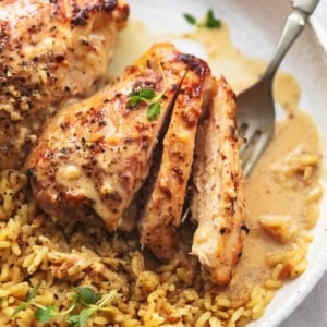 up close view of sliced, cooked chicken thighs with rice and fork on plate