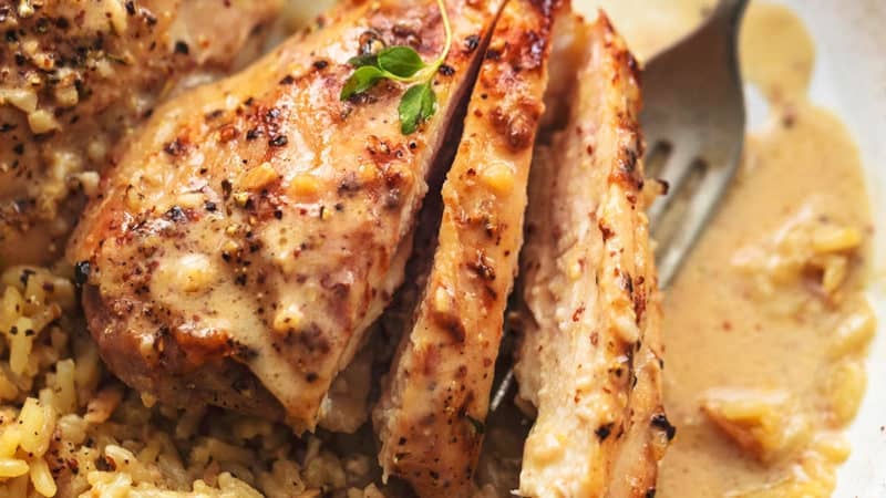 up close view of sliced, cooked chicken thighs with rice and fork on plate