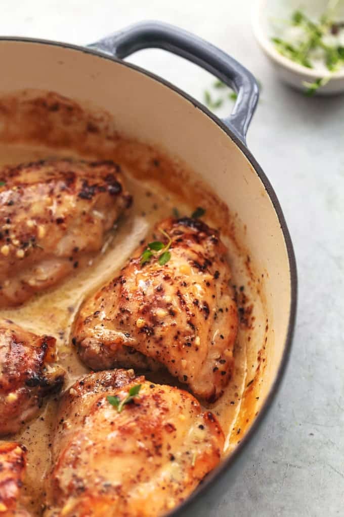 three chicken thighs cooked in creamy sauce in a skillet