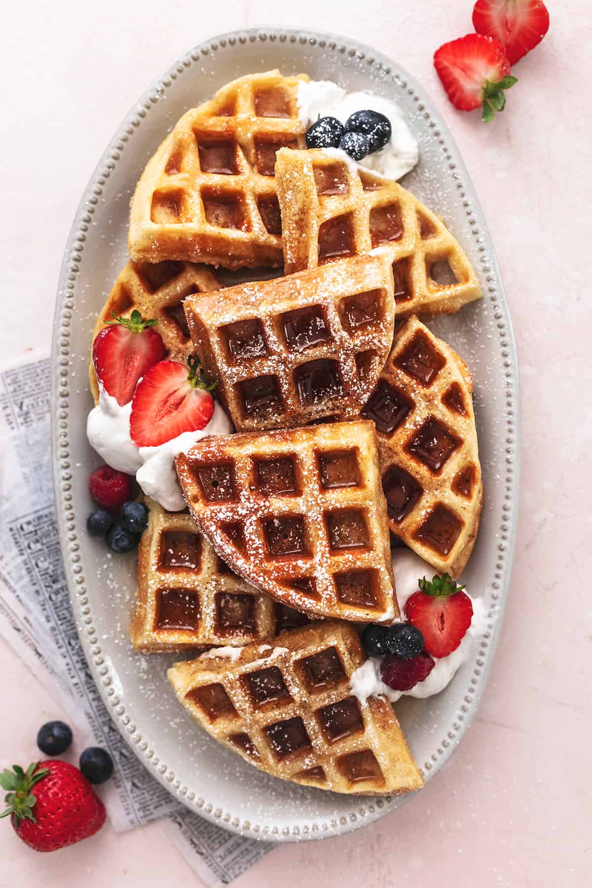 waffles on a plate with berries and whipped cream